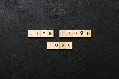 Canlı kahkahalar Tahta blokta yazılı aşk kelimesi. Canlı kahkahalar Çimento masasında aşk metni desing, konsept için.