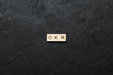 Tahta blokta OKR kelimesi yazıyor. Objective Key 'in kısaltması çimento masadaki metin desing, konsept için.