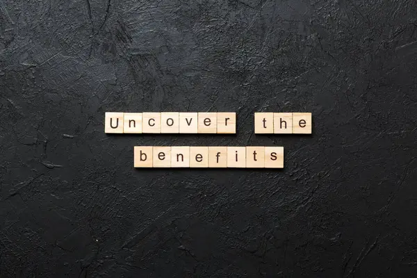 stock image uncover the benefits word written on wood block. uncover the benefits text on table, concept.