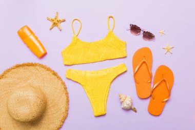 Kadın mayosu ve plaj aksesuarları düz manzarada yatıyordu. Renkli arka planda bikinili üst manzara. Tatil kavramı kopyalama alanı.