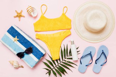 Kadın mayosu ve plaj aksesuarları düz manzarada yatıyordu. Renkli arka planda bikinili üst manzara. Tatil kavramı kopyalama alanı.