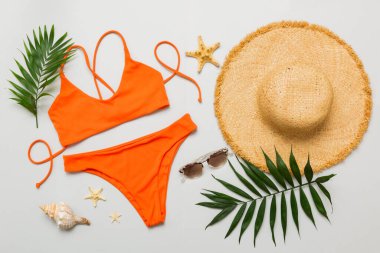 Kadın mayosu ve plaj aksesuarları düz manzarada yatıyordu. Renkli arka planda bikinili üst manzara. Tatil kavramı kopyalama alanı.