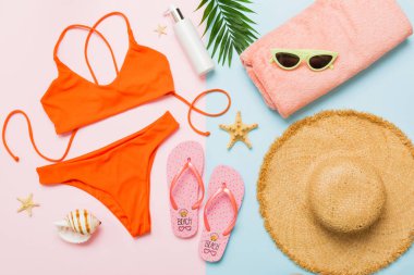 Kadın mayosu ve plaj aksesuarları düz manzarada yatıyordu. Renkli arka planda bikinili üst manzara. Tatil kavramı kopyalama alanı.