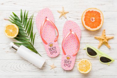 Arka planda plaj aksesuarları olan parmak arası terliklerin üst görünümü. Tropik yaz tatili konsepti.