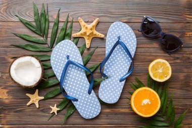 Arka planda plaj aksesuarları olan parmak arası terliklerin üst görünümü. Tropik yaz tatili konsepti.