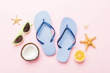 Arka planda plaj aksesuarları olan parmak arası terliklerin üst görünümü. Tropik yaz tatili konsepti.