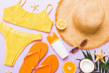 Yüzme havuzu aksesuarı konsepti. Masadaki plaj eşyalarının üst görüntüsü, parlak bikini, hasır şapka ve güneş kremi. Renkli plaj kıyafeti. Üst Görünüm Düz yatar, Boşluğu kopyala.