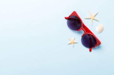 Masa arkasında deniz kabuğu olan güneş gözlükleri. Yaz arkaplanında güneş gözlüğü. Metin için kopyalama alanı olan üst görünüm düzlüğü.