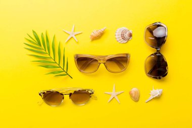 Masa arkasında deniz kabuğu olan güneş gözlükleri. Yaz arkaplanında güneş gözlüğü. Metin için kopyalama alanı olan üst görünüm düzlüğü.