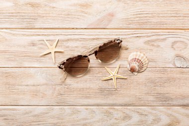 Masa arkasında deniz kabuğu olan güneş gözlükleri. Yaz arkaplanında güneş gözlüğü. Metin için kopyalama alanı olan üst görünüm düzlüğü.