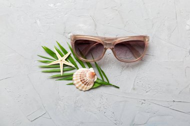 Masa arkasında deniz kabuğu olan güneş gözlükleri. Yaz arkaplanında güneş gözlüğü. Metin için kopyalama alanı olan üst görünüm düzlüğü.