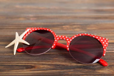Masa arkasında deniz kabuğu olan güneş gözlükleri. Yaz arkaplanında güneş gözlüğü. Metin için kopyalama alanı olan üst görünüm düzlüğü.