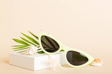 Masa arkasında deniz kabuğu olan güneş gözlükleri. Yaz arkaplanında güneş gözlüğü. Metin için kopyalama alanı olan üst görünüm düzlüğü.