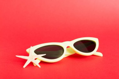 Masa arkasında deniz kabuğu olan güneş gözlükleri. Yaz arkaplanında güneş gözlüğü. Metin için kopyalama alanı olan üst görünüm düzlüğü.