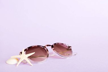 Masa arkasında deniz kabuğu olan güneş gözlükleri. Yaz arkaplanında güneş gözlüğü. Metin için kopyalama alanı olan üst görünüm düzlüğü.