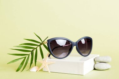 Masa arkasında deniz kabuğu olan güneş gözlükleri. Yaz arkaplanında güneş gözlüğü. Metin için kopyalama alanı olan üst görünüm düzlüğü.