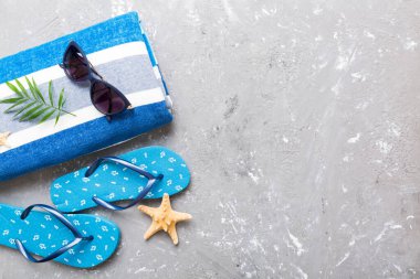 Yaz güneşlenme sahili arka planı, güneş gözlükleri, parmak arası terlikler ve havlu, metin için fotokopi alanı olan üstten manzara.