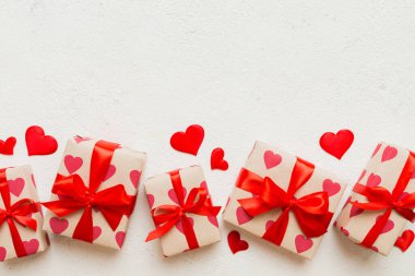 Top view photo of valentine day decorations gift box with red ribbon bow on colored background. Holiday gift boxes with top view.