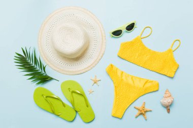 Kadın mayosu ve plaj aksesuarları düz manzarada yatıyordu. Renkli arka planda bikinili üst manzara. Tatil kavramı kopyalama alanı.