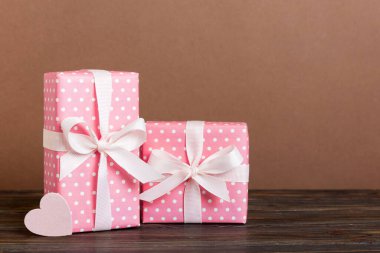 gift box with red bow and red heart on colored background. Perspective view. Flat lay.