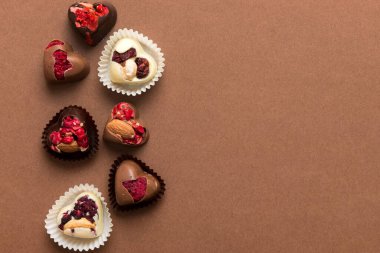 chocolate sweets in the form of a heart with fruits and nuts on a colored background. top view with space for text, holiday concept.