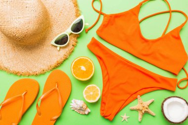 Yüzme havuzu aksesuarı konsepti. Masadaki plaj eşyalarının üst görüntüsü, parlak bikini, hasır şapka ve güneş kremi. Renkli plaj kıyafeti. Üst Görünüm Düz yatar, Boşluğu kopyala.