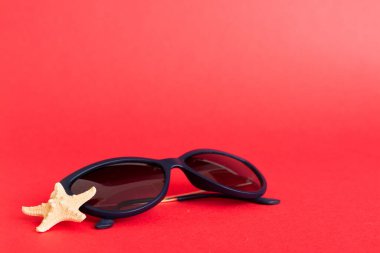 Masa arkasında deniz kabuğu olan güneş gözlükleri. Yaz arkaplanında güneş gözlüğü. Metin için kopyalama alanı olan üst görünüm düzlüğü.