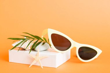 Masa arkasında deniz kabuğu olan güneş gözlükleri. Yaz arkaplanında güneş gözlüğü. Metin için kopyalama alanı olan üst görünüm düzlüğü.