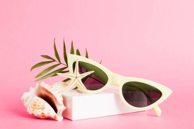 Masa arkasında deniz kabuğu olan güneş gözlükleri. Yaz arkaplanında güneş gözlüğü. Metin için kopyalama alanı olan üst görünüm düzlüğü.