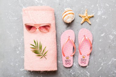 Yaz güneşlenme sahili arka planı, güneş gözlükleri, parmak arası terlikler ve havlu, metin için fotokopi alanı olan üstten manzara.