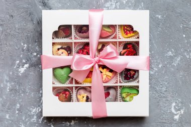 Box with sweet chocolate candies on color background, Various candy sweets. Valentines day gift box. Top view flat lay with copy space.