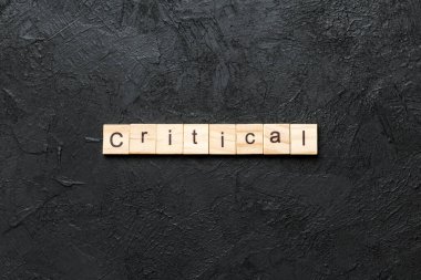 Tahta blokta kritik bir kelime yazıyor. masadaki kritik metin, konsept.