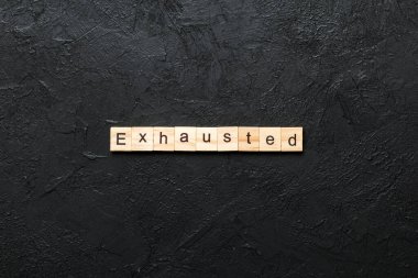 Tahta bloğa yazılmış tükenmiş bir kelime. Çimento masasında yorulmuş metin desing, konsept için.