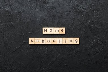 Ahşap blokta evde eğitim kelimesi yazıyor. Masada evde eğitim metni, konsept.