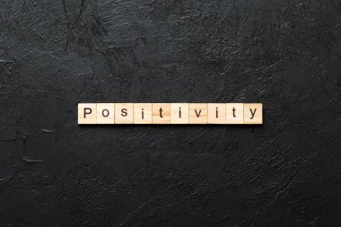 Tahta bloğa olumlu bir kelime yazılmış. Çimento sehpası üzerinde pozitif metin desing, konsept için.