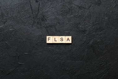 Tahta blokta yazılı FLSA kelimesi. Adil Çalışma Standartları Yasası metni masa, konsept.