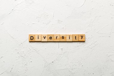 Diversity word written on wood block. Diversity text on cement table for your desing, concept. clipart