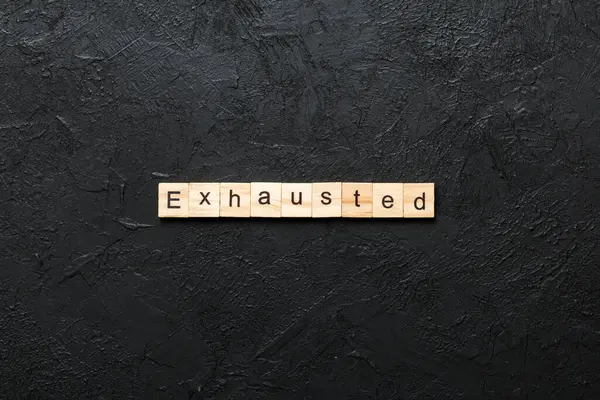 Tahta bloğa yazılmış tükenmiş bir kelime. Çimento masasında yorulmuş metin desing, konsept için.