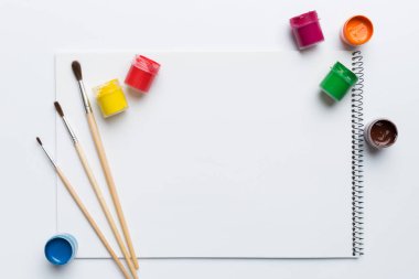 Albüm sayfaları, boyalar, kalemler, renkli arka planda fırçalar. Boşluğu olan üst görünüm. Yaratıcılık için işyeri. ev öğretmenliği kavramı çizimi.