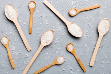 Ahşap arka planda bir sürü tahta kaşıkta tuz. Farklı tuzlu kaşıklar..