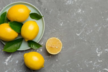 Taze kesilmiş limon ve tüm limonları renkli arka planda yuvarlak tabakta. Yemek ve içecek malzemeleri hazırlanıyor. Sağlıklı beslenme teması üst görünüm kopyalama alanı.