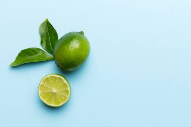 Yeşil yapraklı kireç meyveleri ve beyaz arka planda yarım dilim kesilmiş. Üst Manzara. Kopyalama alanı olan düz.