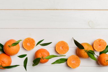 Renkli arkaplanda yeşil yaprakları, üst görünümü, metin için alanı olan bir sürü olgun mandalina..