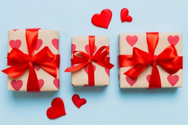 Top view photo of valentine day decorations gift box with red ribbon bow on colored background. Holiday gift boxes with top view.
