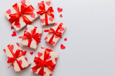 Top view photo of valentine day decorations gift box with red ribbon bow on colored background. Holiday gift boxes with top view.