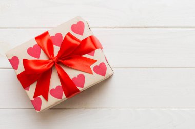 Top view photo of valentine day decorations gift box with red ribbon bow on colored background. Holiday gift boxes with top view.