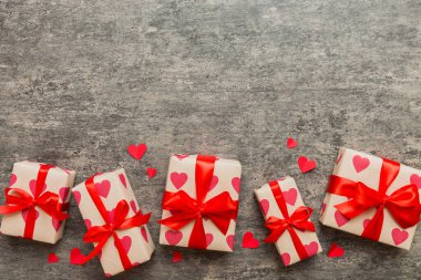 Top view photo of valentine day decorations gift box with red ribbon bow on colored background. Holiday gift boxes with top view.