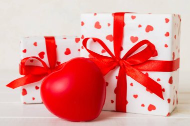 gift box with red bow and red heart on colored background. Perspective view. Flat lay.