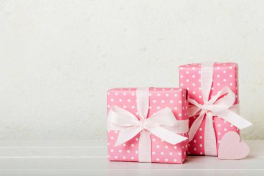gift box with red bow and red heart on colored background. Perspective view. Flat lay.