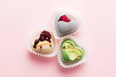 chocolate sweets in the form of a heart with fruits and nuts on a colored background. top view with space for text, holiday concept.